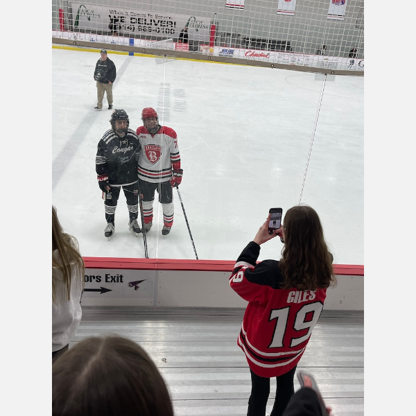 Girls Club founder Delaney Giles snaps a photo of a Bradley hockey player posing with one of his opponents