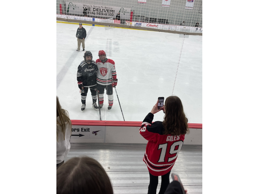 Girls Club founder Delaney Giles snaps a photo of a Bradley hockey player posing with one of his opponents