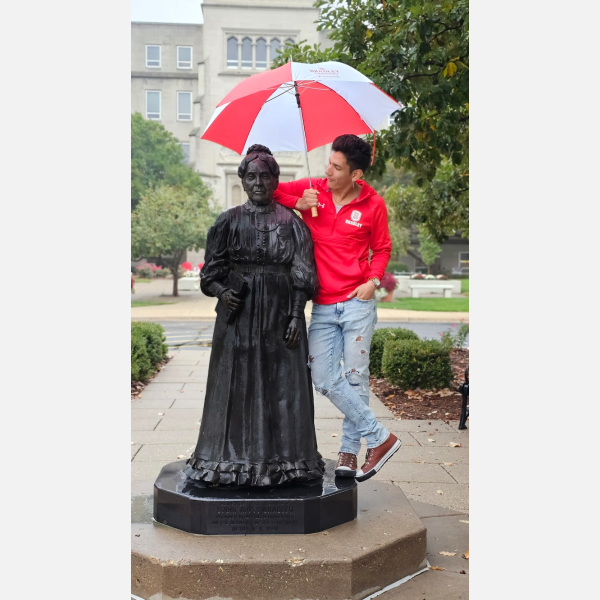 Rodrigo Alvarez Gonzalez poses in the rain with a statue of Lydia Moss Bradley.