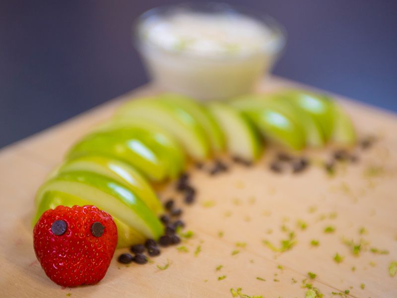 A caterpillar made of apples, raisins and a strawberry