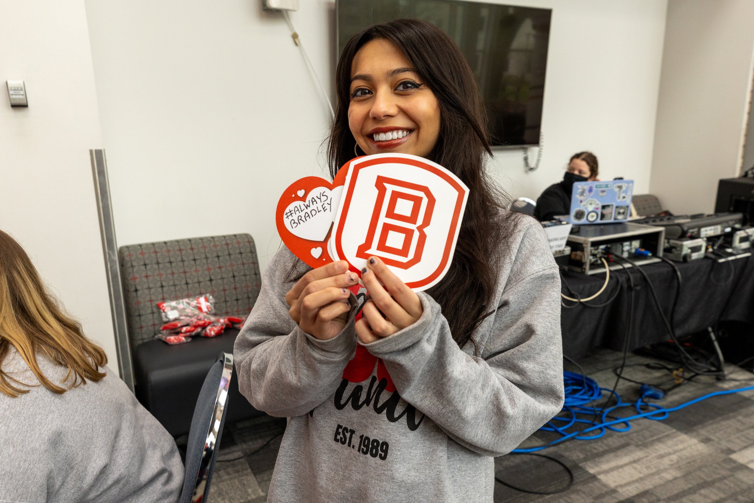 A woman smiling showing off a Bradley Shield sticker to the camera