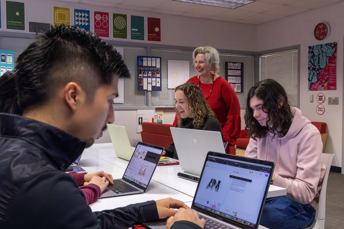 An classroom of students at their computers with an instructor talking