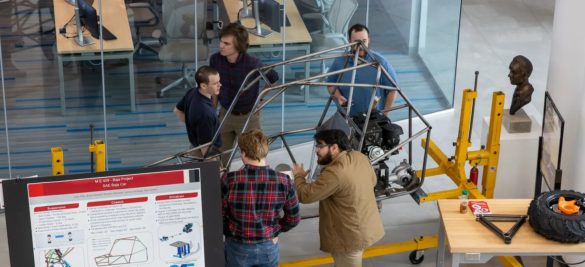 Several engineering students gathered around their baja car project