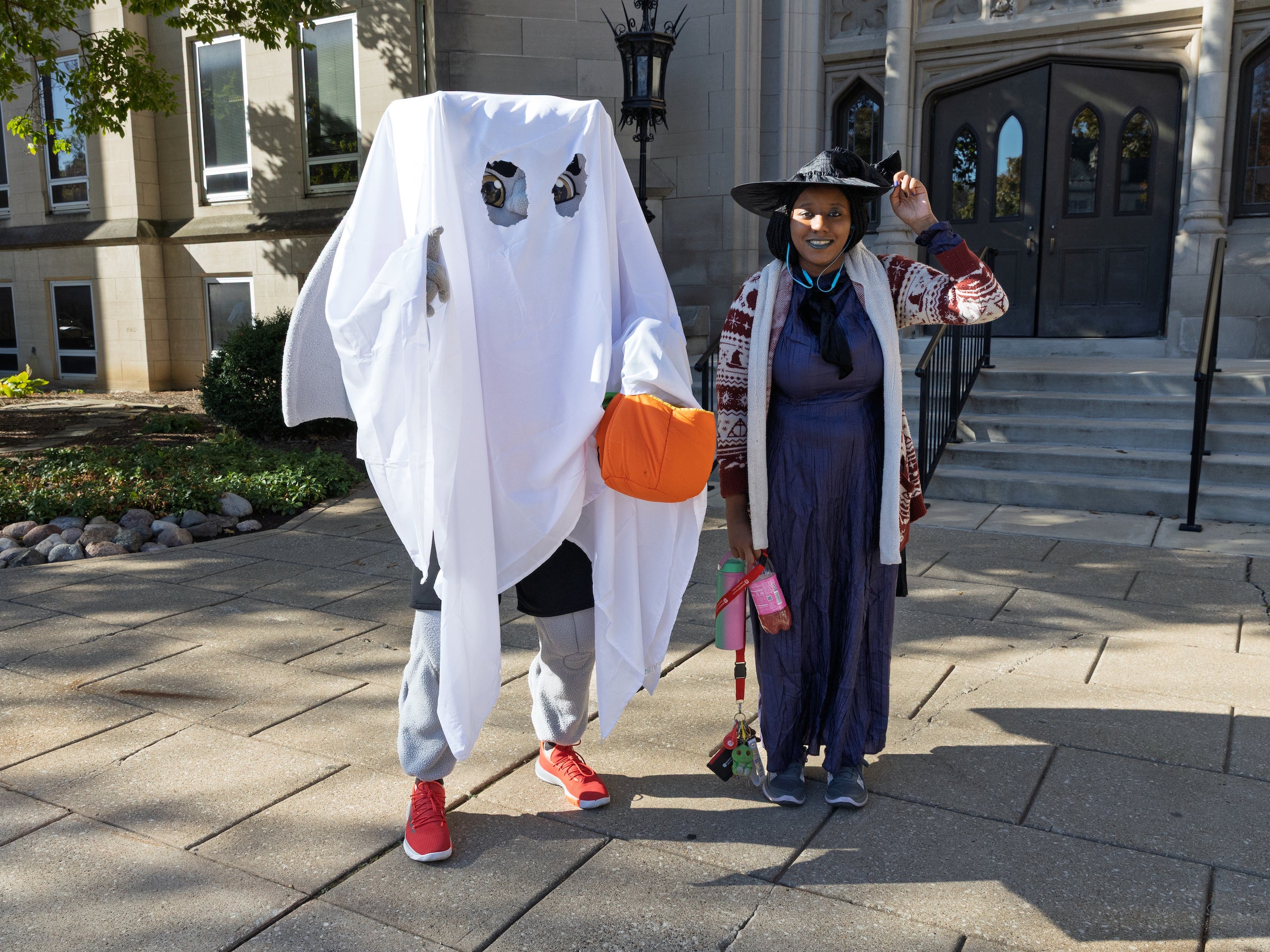 Kaboom mascot dressed as a ghost with a student dressed as a witch for halloween