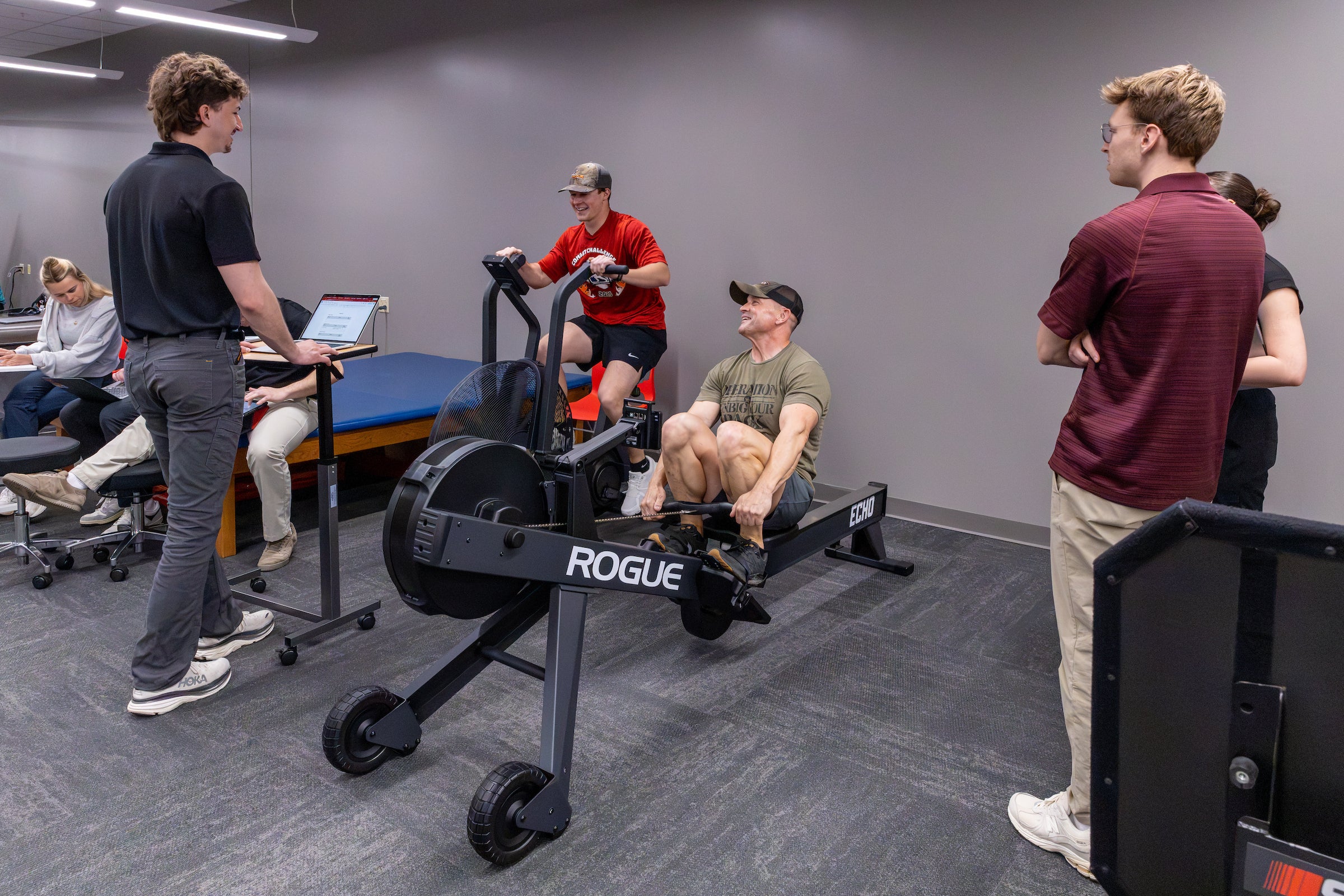 A clinician monitoring patients on an exercise bike and row machine