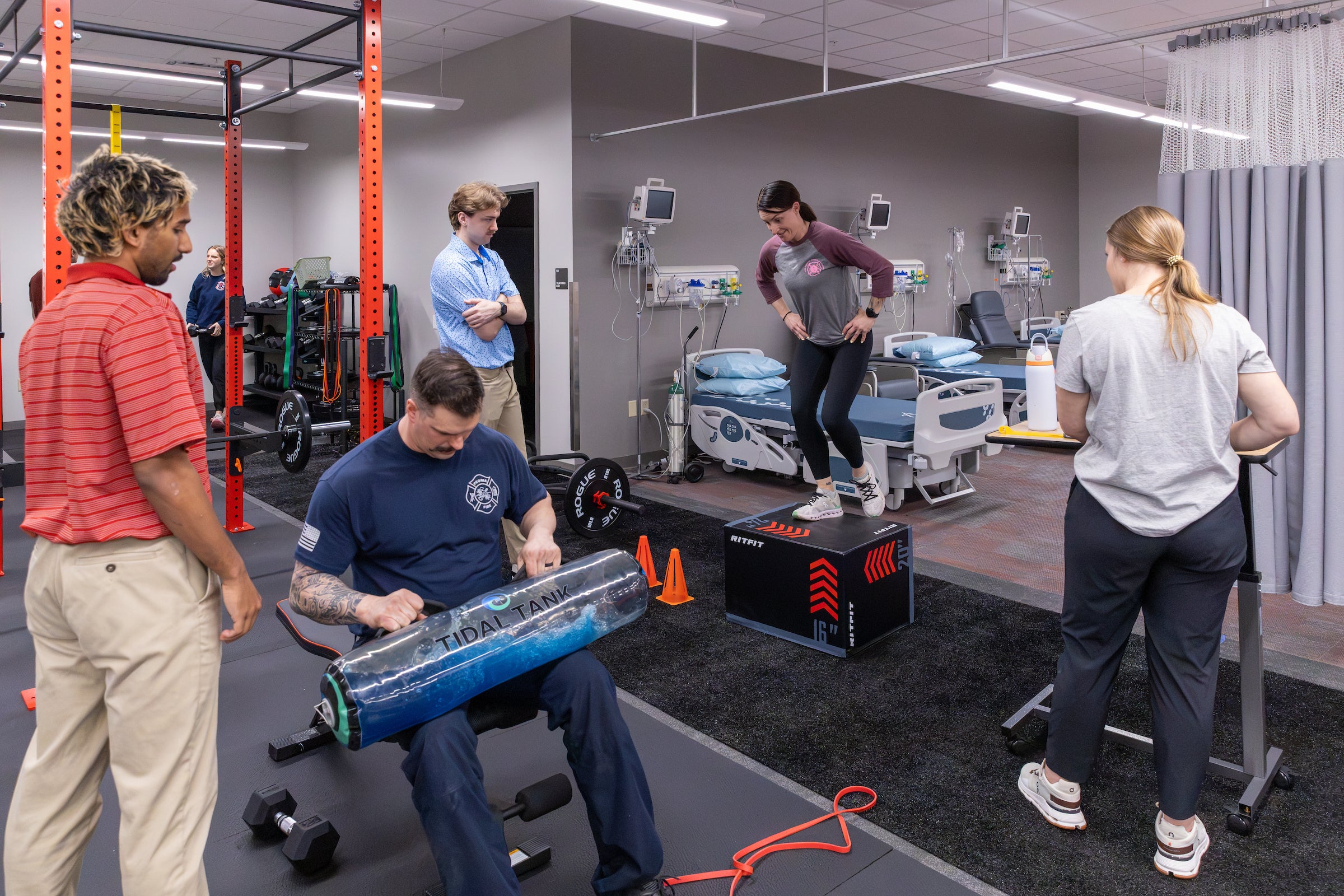 A busy physical therapy clinic with patients doing exercises around the room with various kinds of equipment