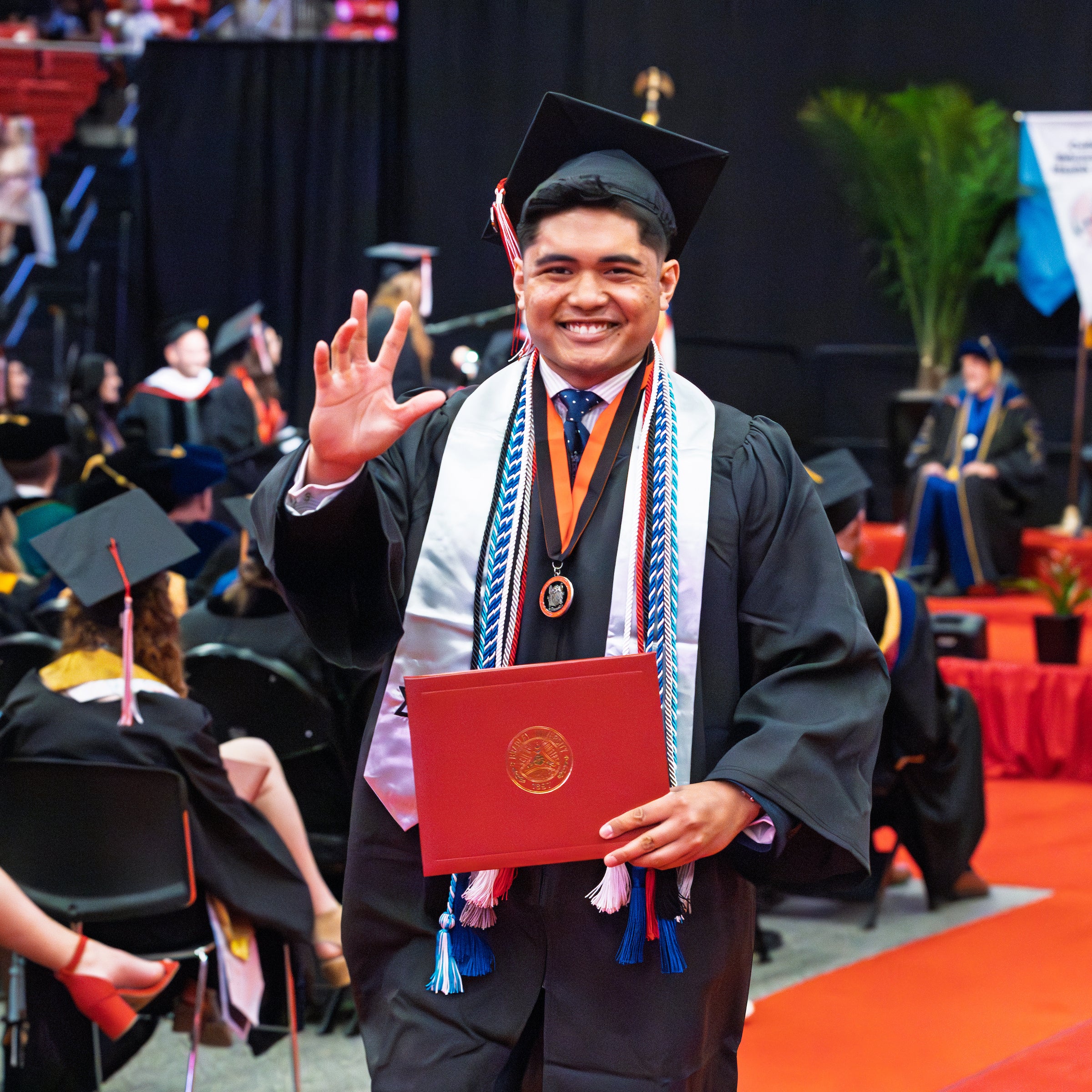Al Cuizon posing for a photo in his graduation robe as he walks during commencement