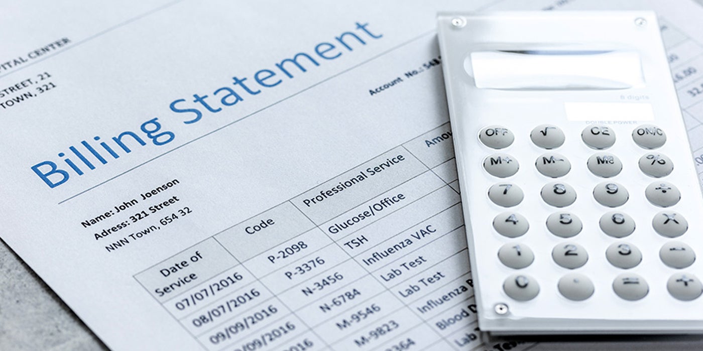 A medical billing laying on a table with a calculator