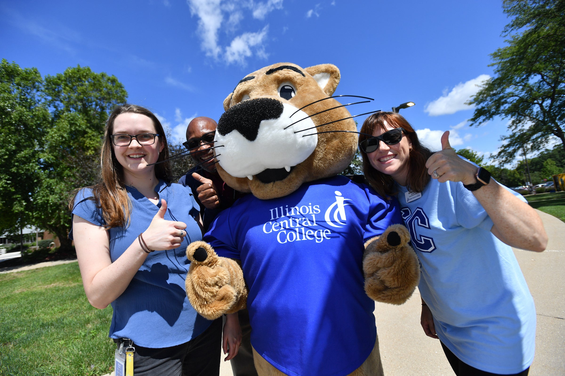 Two female Illinois Central College students posing with the mascot with thumbs up