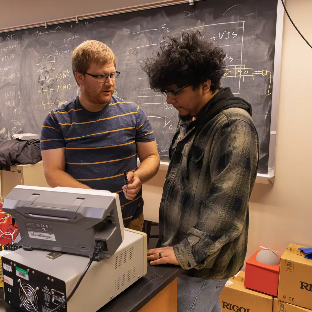 A student and professor in a classroom discussing instrumentation