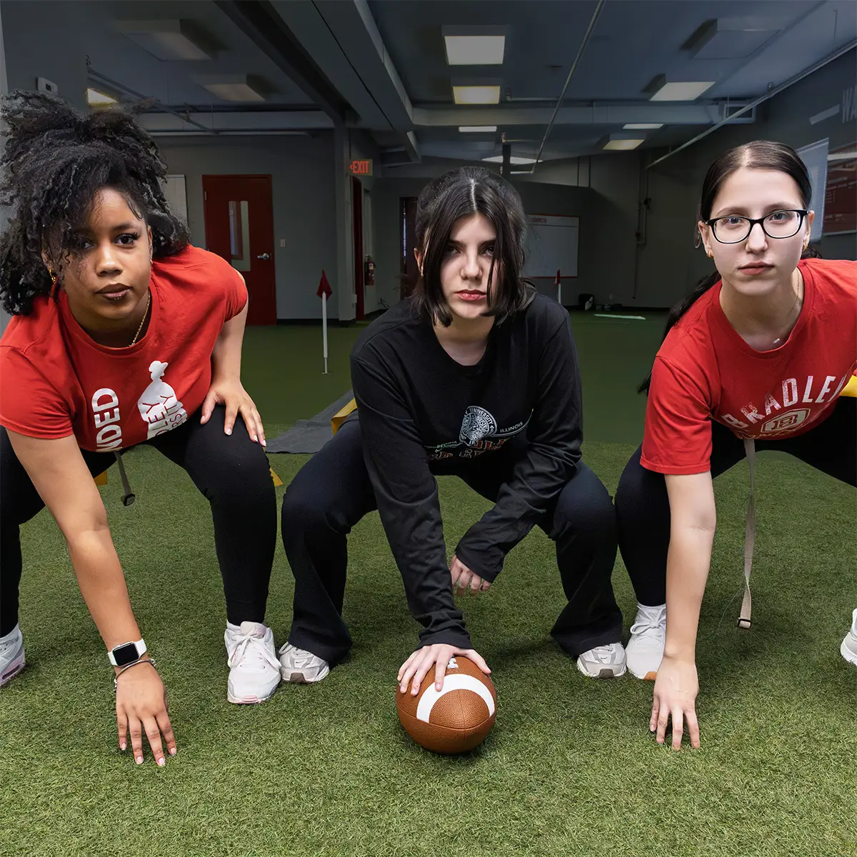 Three women posing in a football formation