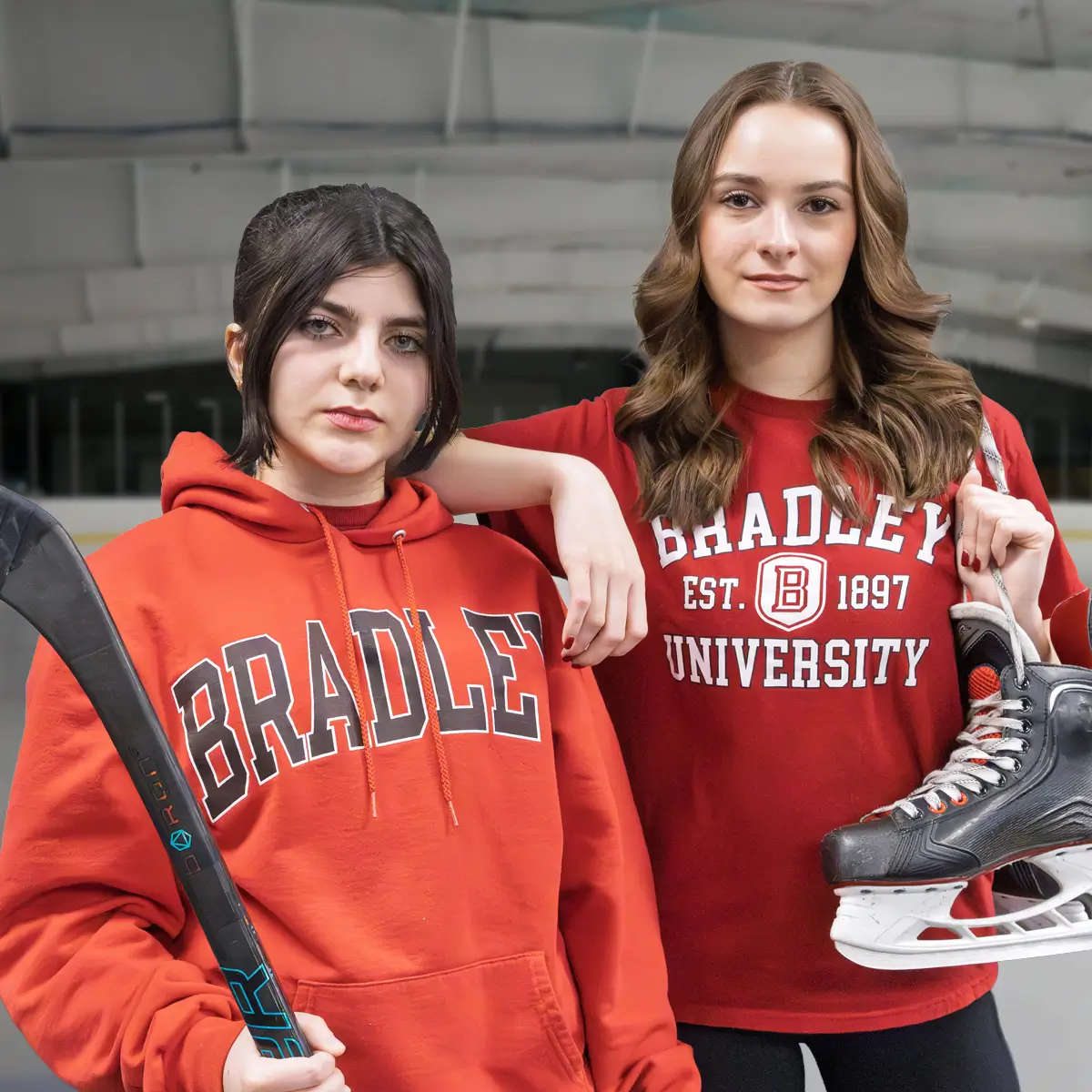 Two women posing with hockey skates and a hockey stick